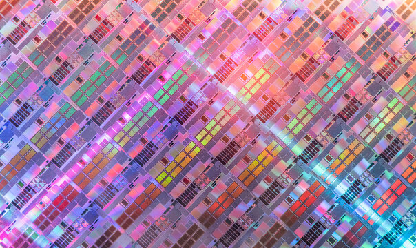 silicon wafer background with microchips reflecting different colors.