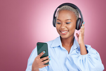 Music, headphones and black woman with phone in studio for streaming, radio or listen on pink background. Smartphone, app and African lady model with online audio, podcast and earphones for album