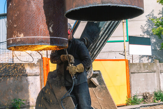 The welder, who was in the bucket of the excavator, performed welding work. Gas welding works on replacement of large pipes of heating mains. Replacement of an outdated heat supply pipeline.