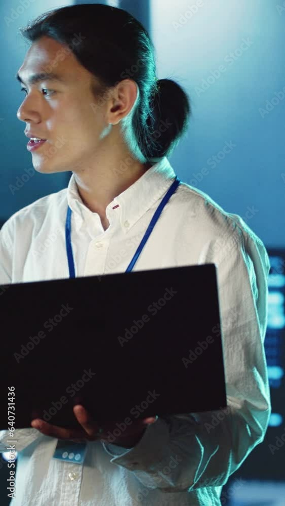 Poster vertical video trained employee strolling through server rows providing processing resources for dif