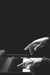 closeup male pianist hands playing piano, isolated on black. black and white. music background
