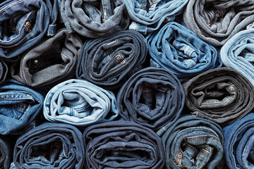 Lots of rolled up jeans. Denim background. Trendy denim clothing, shopping, fashion, consumption.