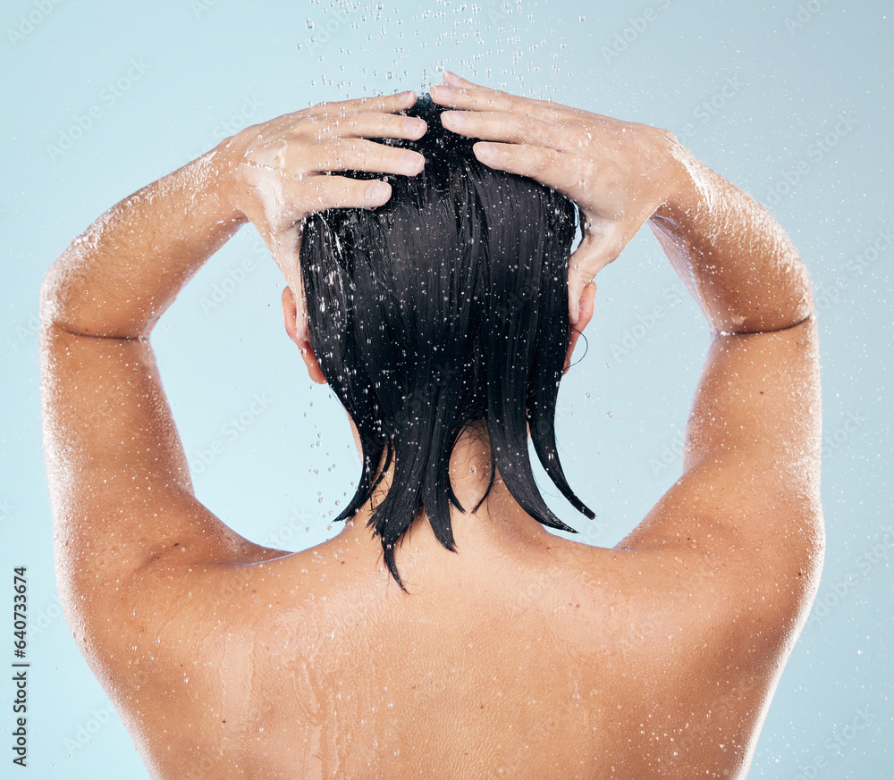 Wall mural Hair care, shower and back of woman cleaning in studio isolated on a blue background. Water splash, hygiene and model washing, bathing and cosmetics for wellness, beauty and body health in bathroom