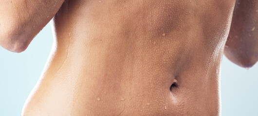 Fototapeta premium Body care, cleaning and stomach of woman in a shower for wellness, hygiene and skincare in studio closeup. Water splash, zoom and abdomen of female model in bathroom for beauty, routine or daily care