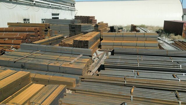 Aerial view of galvanized iron pipes stack and steel rectangular bars of metal