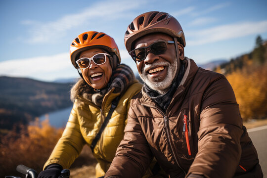 pareja de jubilados, con ropa de abrigo, cascos y gafas de sol, montando en bicicleta por la naturaleza, como parte de un viaje de aventura para seniors