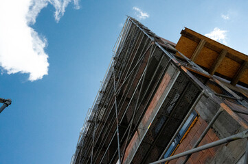 Obraz premium Scaffolding on multi storey building facade during facade renovation. Bright sunny day.