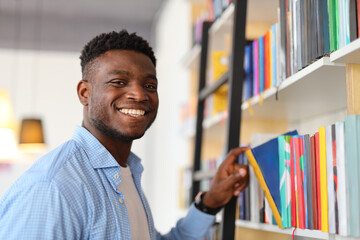 A young, intelligent student in a library, happily engrossed in studying amidst shelves of books.