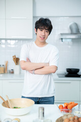Happy portrait of asian young man of sit a cheerful preparing food and enjoy cook cooking with vegetables, while standing on a kitchen Condo life or home