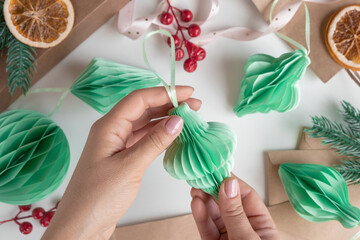 Female hands unfold paper Christmas honeycomb ornaments. Handmade foldable plastic free decor....