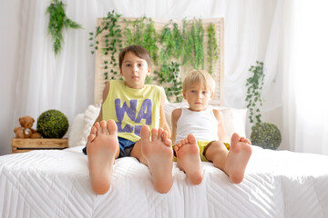 Happy positive children, tickling on the feet, having fun together, boy brothers at home having wonderful day of joy © Tomsickova