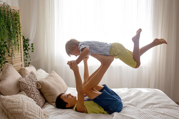 Happy positive children, tickling on the feet, having fun together, boy brothers at home having...