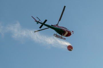 Bottom view of a helicopter carrying a container of water to put out a fire
