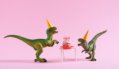 Cute happy green dinosaurs in birthday hats with cake with flaming candles on pastel pink...