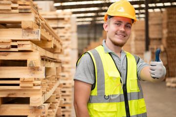 Portrait of warehouse worker checking stock of wooden pallets in storage warehouse.