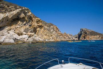 at medes island a group of kayaks paddles in front of the steep cliffs and blue sky