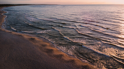Sea waves at sunset on the Baltic Sea. A sandy beach in Kolobřeh. Taken from a drone. Kołobrzeg is city in Poland. Top down