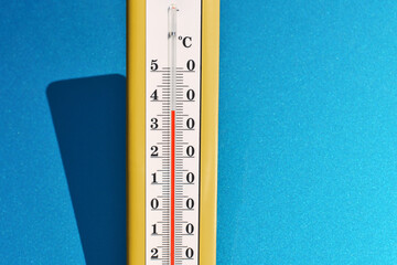 A yellow thermometer on a blue background. Summer temperature records.