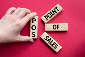 POS - Point Of Sales symbol. Wooden cubes with words POS. Businessman hand. Beautiful red...