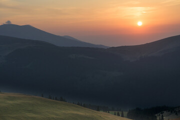 Spectacular sunset in a beautiful mountain landscape. The sun sets behind the mountains.