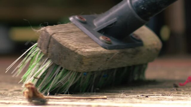 Cleaning old worn wooden decking with brush 