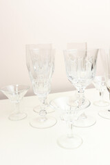 Vintage crystal glasses in front of beige background. Minimal composition.