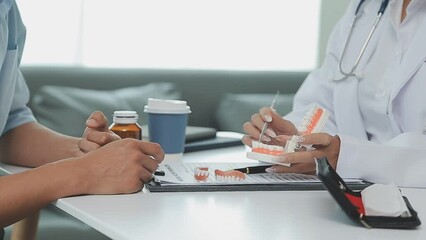 Dentists are discussing dental problems at report x-ray image on laptop screen to patients.