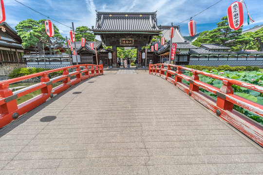 Nagano City, Japan - August 04, 2017 : Bridge over the Hosho Ike pond and people wearing wedding Kimonos at Daimon gate of Daikanjin Temple located in the Zenko-ji Temple complex