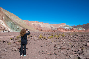 woman black dressed taking a picture at the landscape of valle arcoiris, antofagasta, atacama, chile