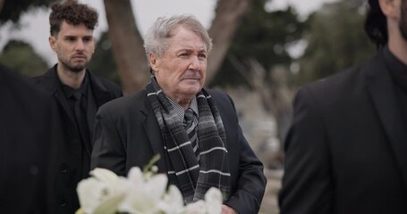 Funeral, death and senior man carry coffin with family in grief, mourning and sad during church service for peace. Memorial, difficult and person with loss walking in the wind with casket at ceremony