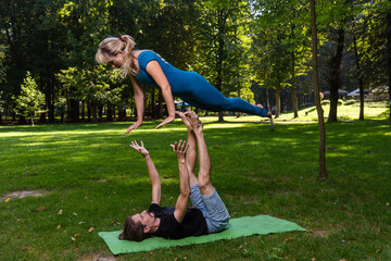 Boy and girl doing acro yoga outdoors in summer in public park