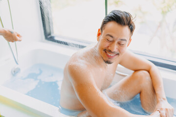 Happy childish funny asian man being take care of showering by his wife.