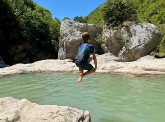 Boy jumping into Syri I Ciklopit pool, Albania.