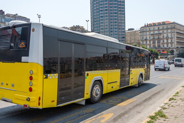 Fototapeta premium Yellow city bus rides through the streets of the route.