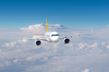 Passenger civil airplane jet flying at flight level high in the sky above the clouds and blue sky.