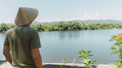 boy with vietnamese hat looking at the river