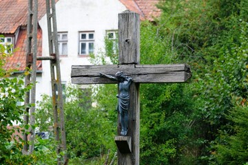 Wooden cross in garden, building in background