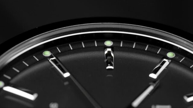 Extreme closeup of  second arrow passing by on clock face. Lengthwise view of luxury swiss watch. Closeup real time shot. Running second arrow. Black clock face.