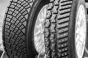 Two types of modern rally tires, studded winter snow and ice tire and asymmetric gravel tire