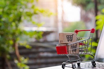 Shopping online. cardboard box with a shopping cart logo in a trolley on laptop keyboard. Shopping...