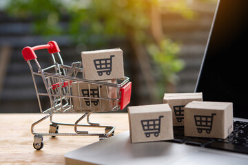 Shopping online. cardboard box with a shopping cart logo in a trolley on laptop keyboard. Shopping...