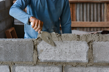 Bricklayer laying bricks on mortar