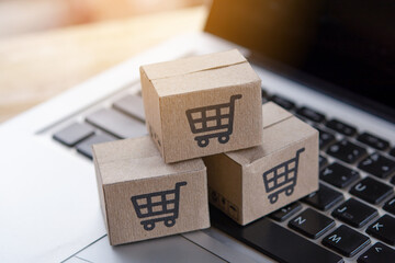Shopping online. Cardboard box with a shopping cart logo on laptop keyboard. Shopping service on The online web. offers home delivery.