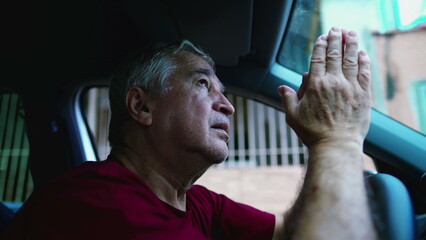 Religious senior man Praying to God during difficult times while sitting inside vehicle, parked in street looking at sky asking for divine help - obrazy, fototapety, plakaty