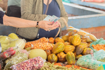 Women shopping at the farmer's market. Local market stall filled with fresh packaged fruits and grains. Shopping for farm products. Colombian money. Supply and demand concept.