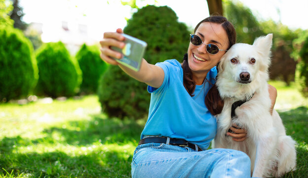 Close up photo of young smiling girl takes selfie with her white Dog outdoor on the lawn. Adoption, rescued, shelter, companion, pet, best friend.