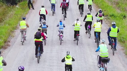 View of bicycle race in the city streets, bike race with a group mass of cyclist athletes in cycling marathon competition, team of bikers on a forest bike path, aerial drone view