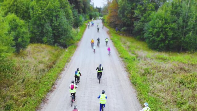 View of bicycle race in the city streets, bike race with a group mass of cyclist athletes in cycling marathon competition, team of bikers on a forest bike path, aerial drone view