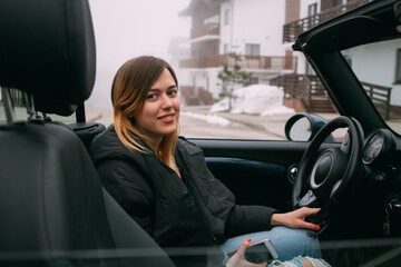 Portrait of a girl in a convertible with an open roof.