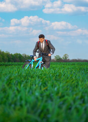 businessman rides a bicycle through a green grass field, the concept of activity, leisure or freelancing